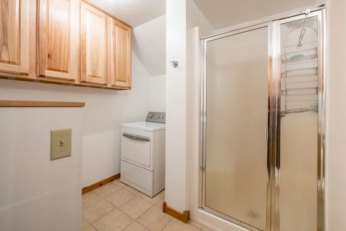 Lower bathroom with walk-in shower, vanity, washer, and laundry access