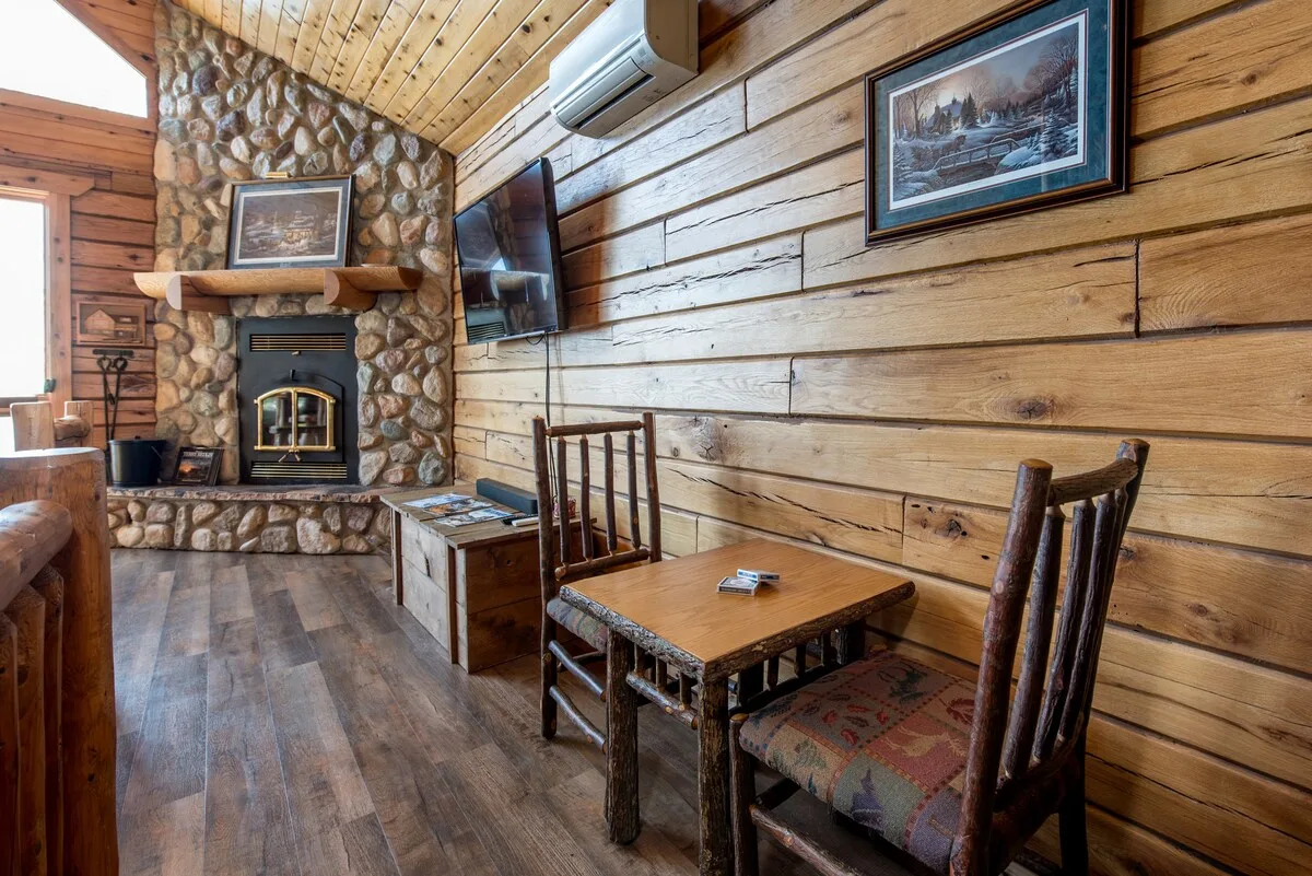 Cozy sitting area beside the stone fireplace with warm log cabin walls