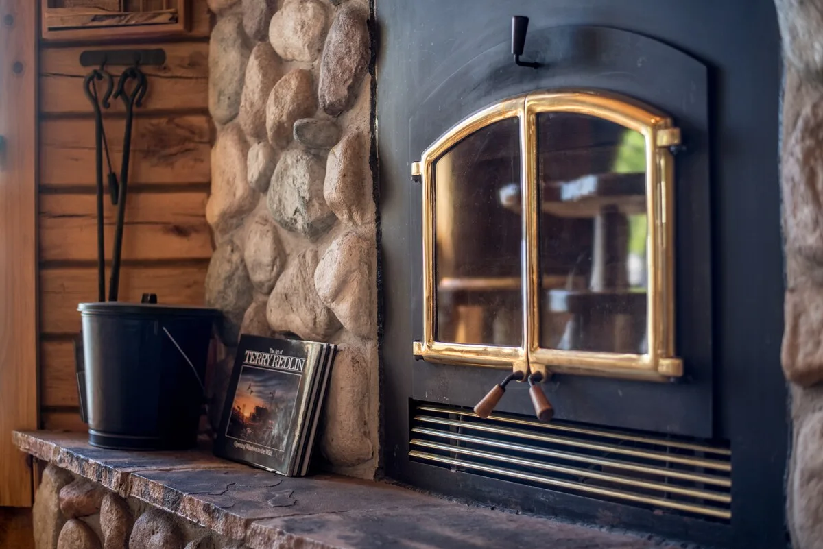 Close-up of the river stone fireplace with rustic log mantel and cabin decor