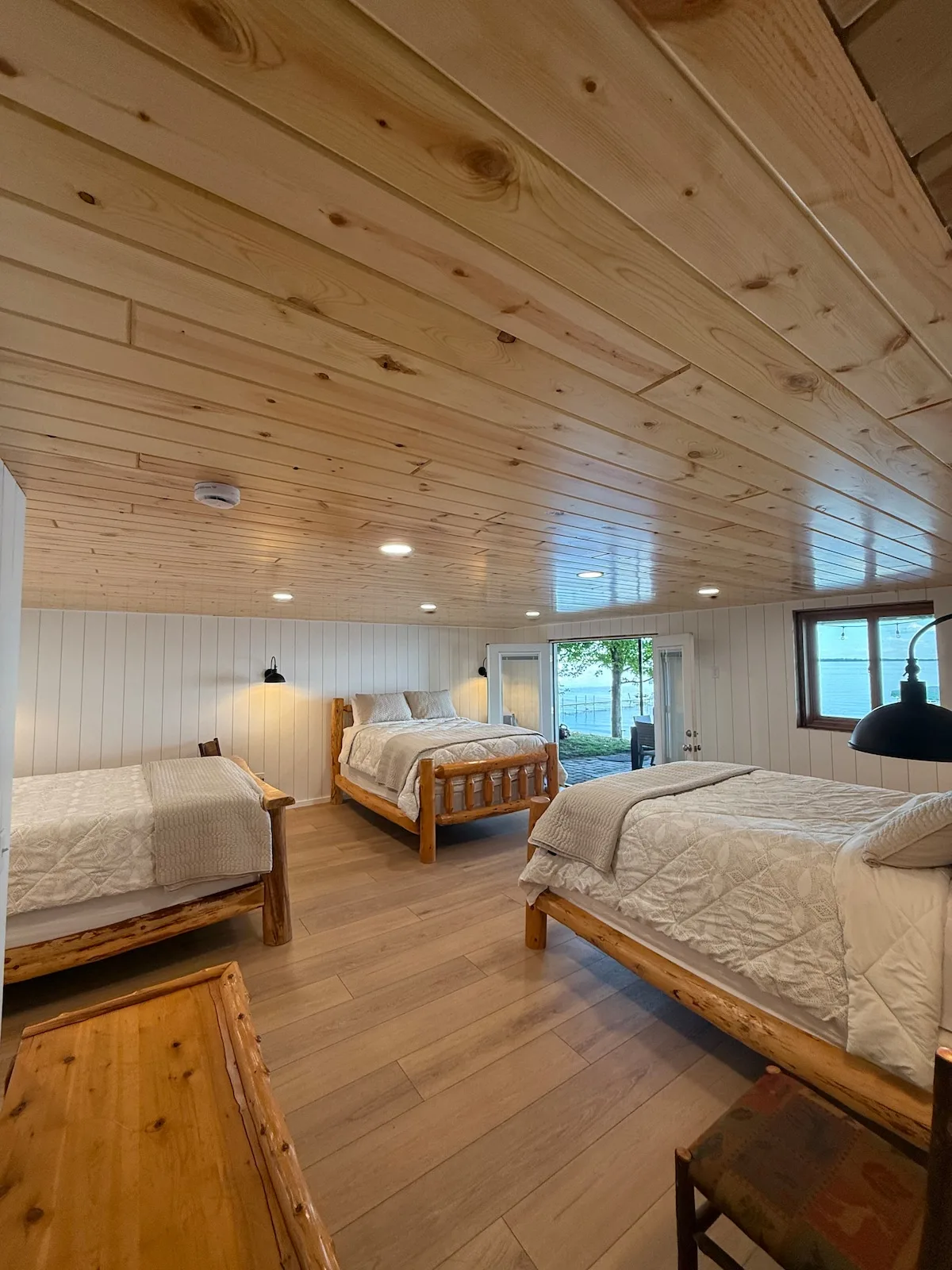 Sandbar Suite wide angle showing three queen beds with log frames and wainscoting