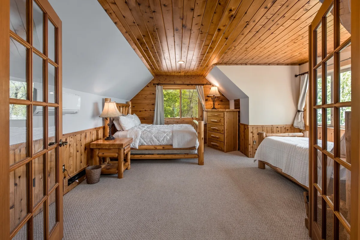 Master Suite with queen log bed, matching nightstands, and scenic lake views through double windows