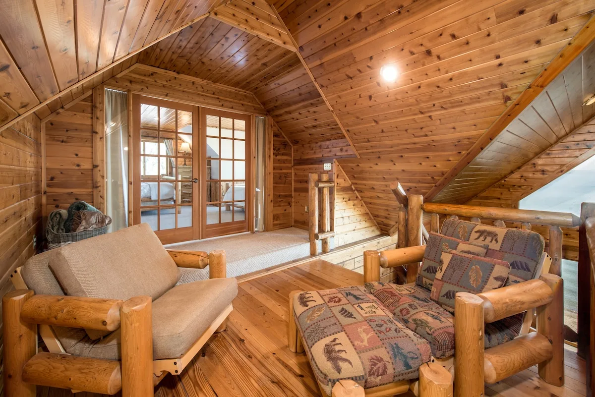 Loft sitting area with log armchairs, quilted cushions, and french doors to the master bedroom