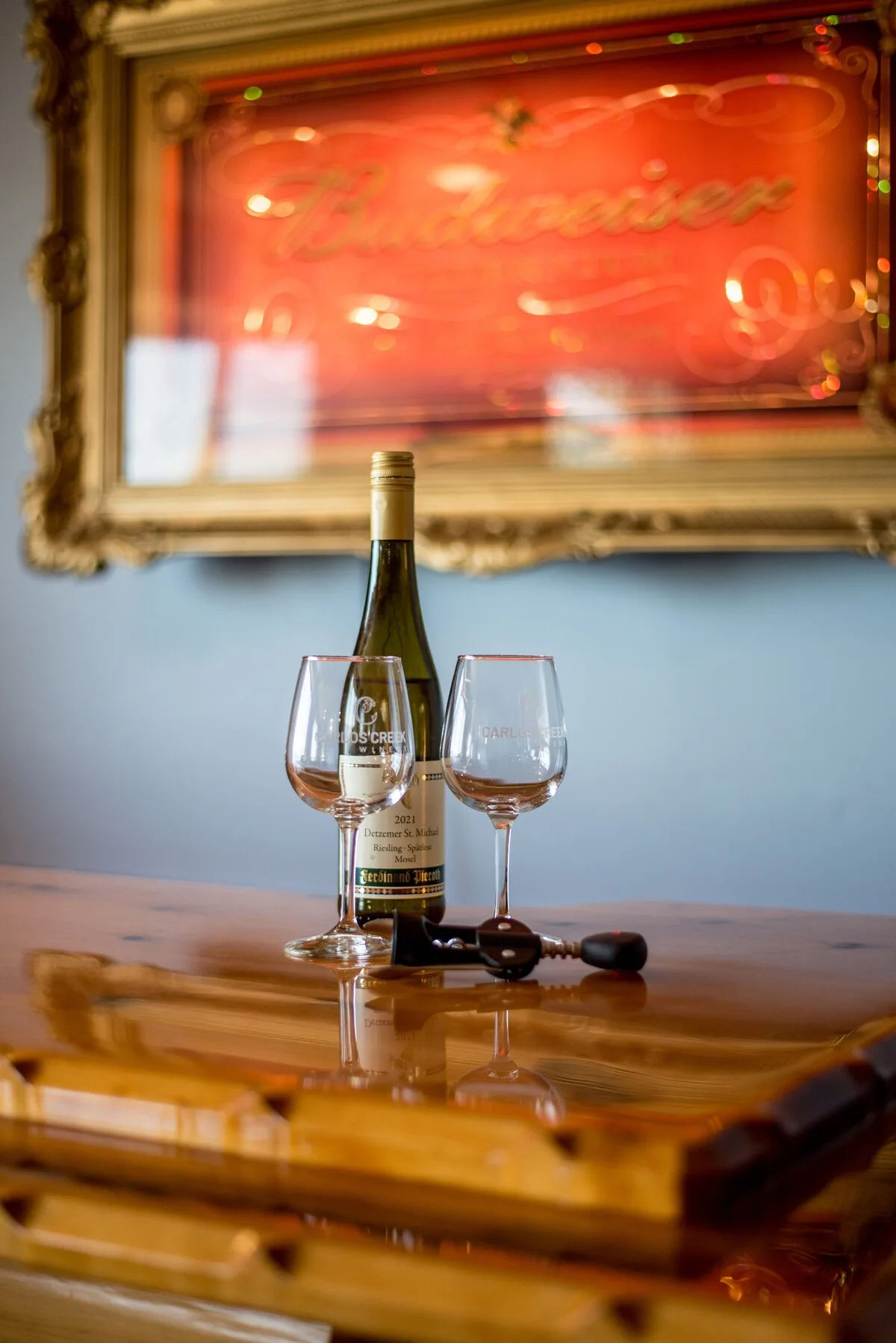 Wine and glasses on the bar with a Budweiser mirror sign in the background