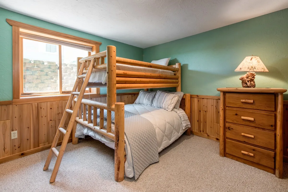Bedroom 3 with log bunk bed, dresser with bear lamp, and teal accent walls