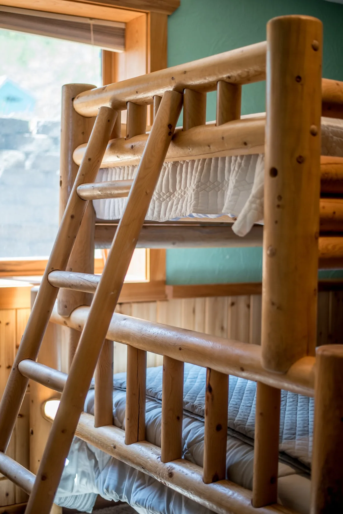 Close-up of the handcrafted log bunk bed with ladder in Bedroom 3