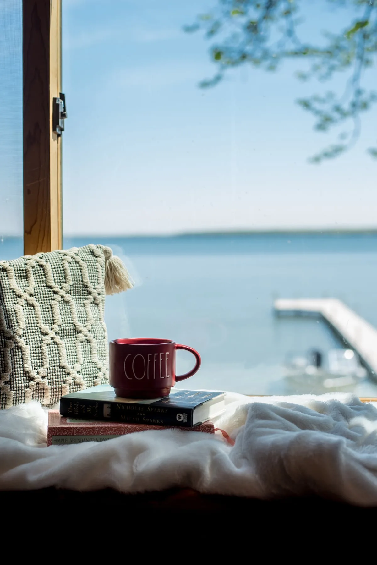Coffee mug on books by the window with dock and Lake Miltona sparkling in the background