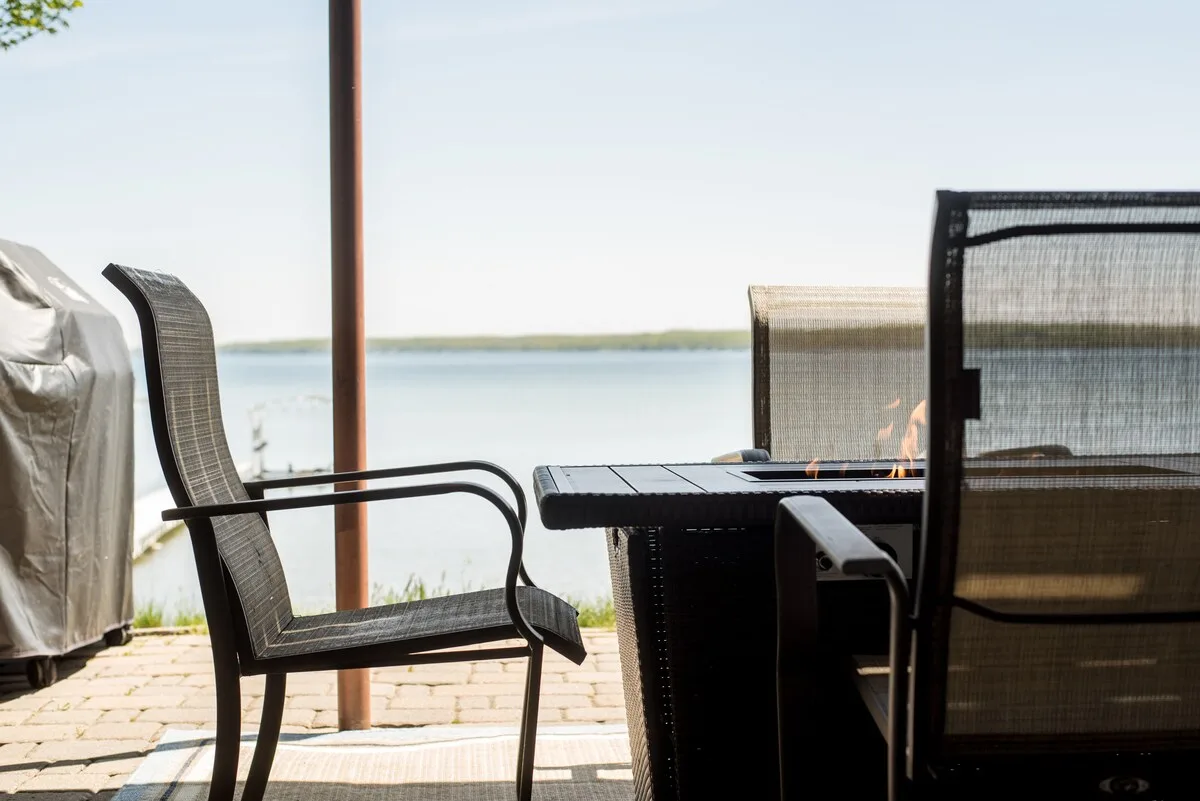 Lakeside patio with outdoor fire table, chairs, and sweeping lake views