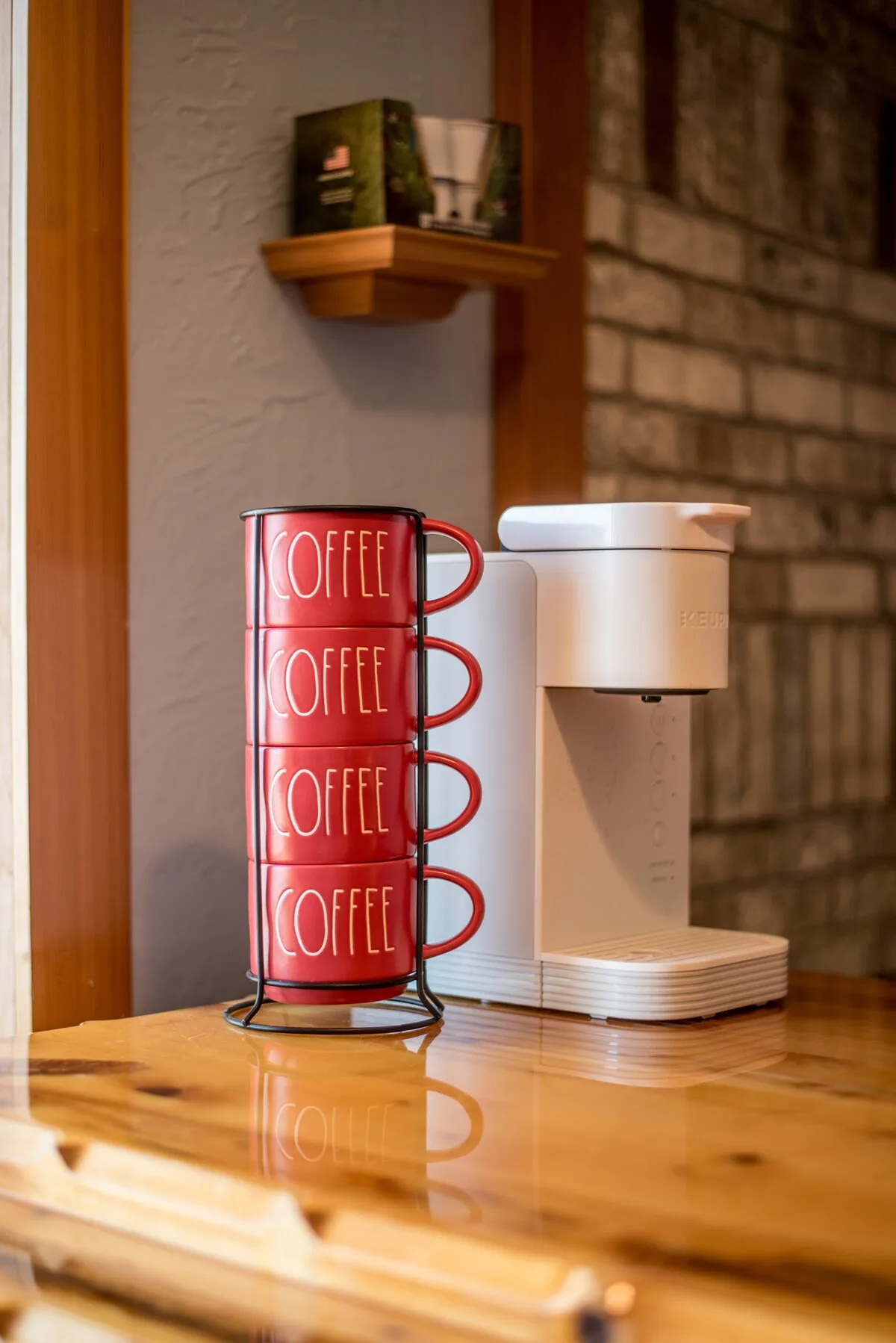 Keurig coffee maker with stacked red coffee mugs on the bar countertop