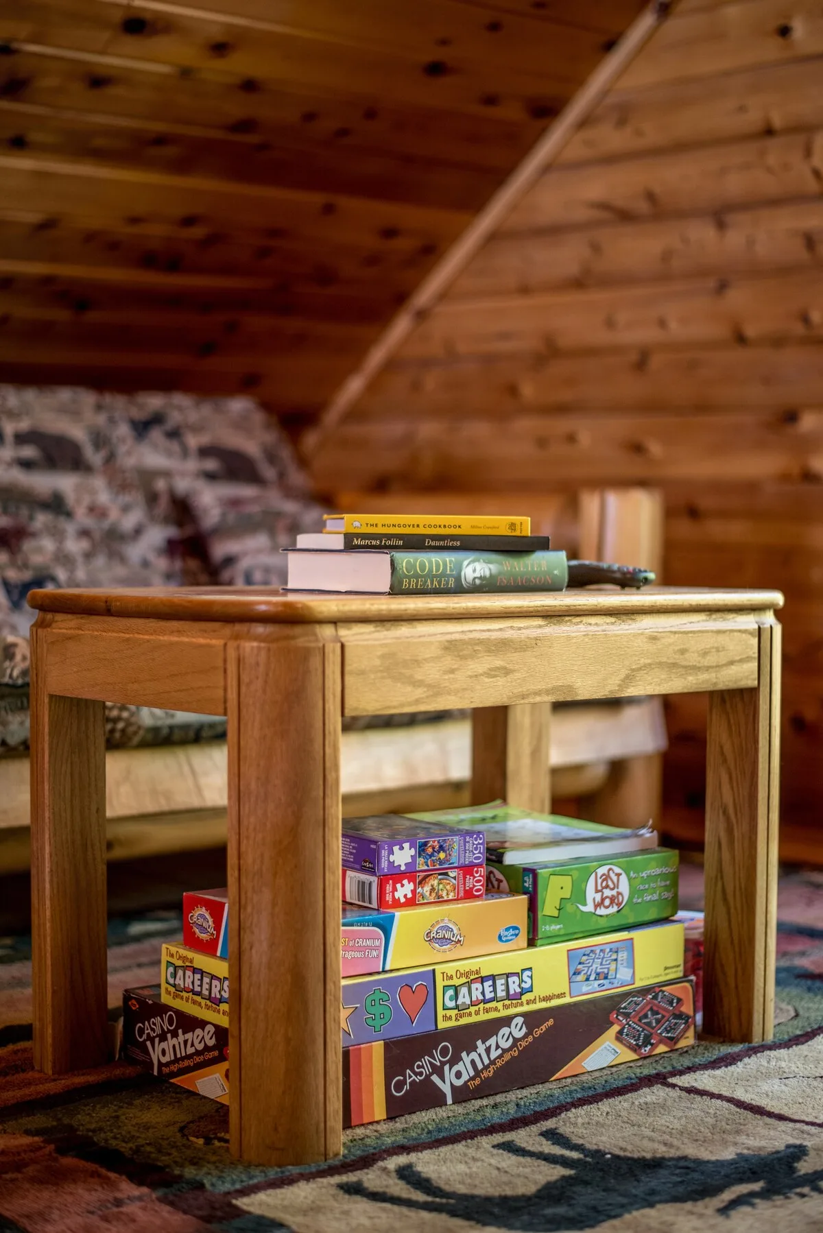 Board games and books on a side table in the loft including Yahtzee, Cranium, and puzzles