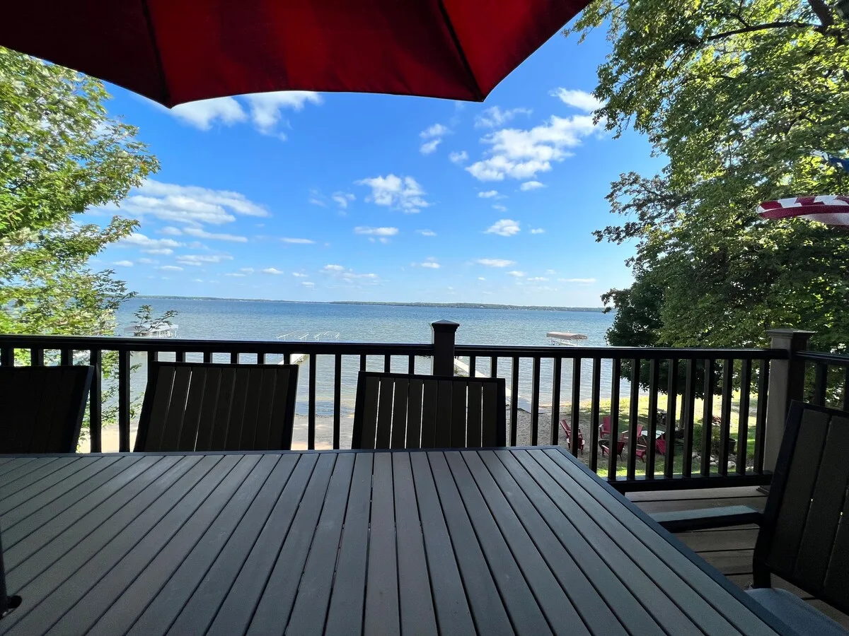 Upper deck dining table under red umbrella overlooking Lake Miltona on a sunny day