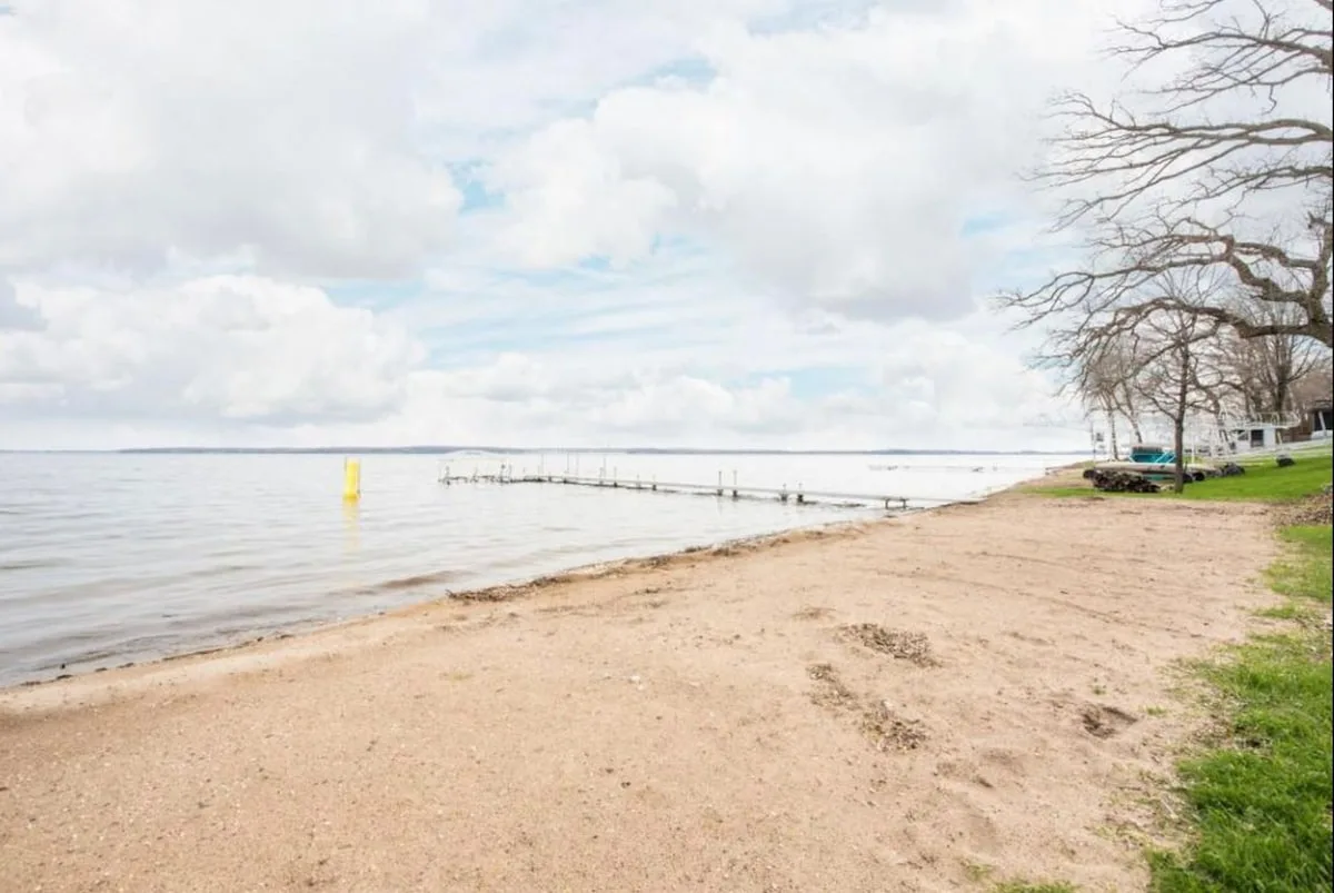 Wide sandy beach on Lake Miltona with gradual entry, private dock, and lush green shoreline