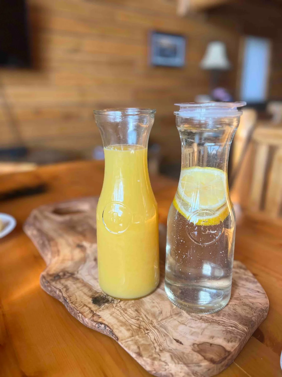Fresh juice and lemon water carafes on a rustic wooden board in the cabin