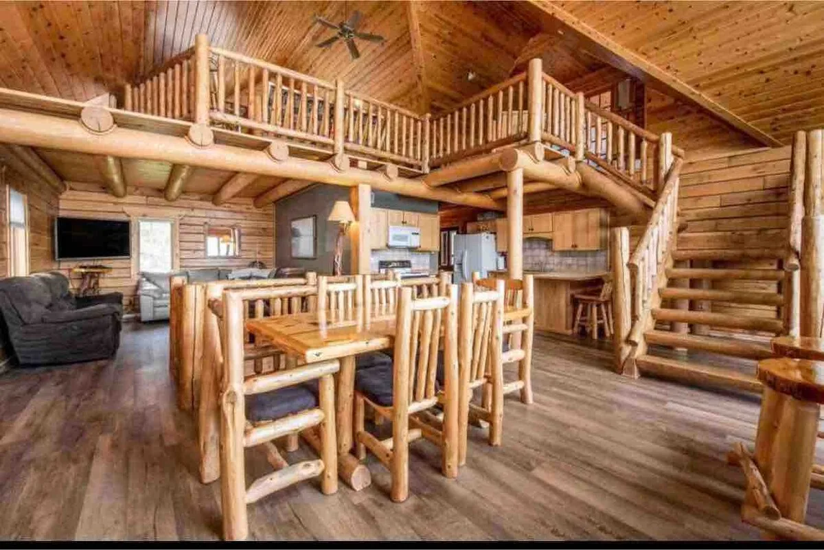 Great room wide angle with log dining table for 8, kitchen, loft balcony, and log staircase